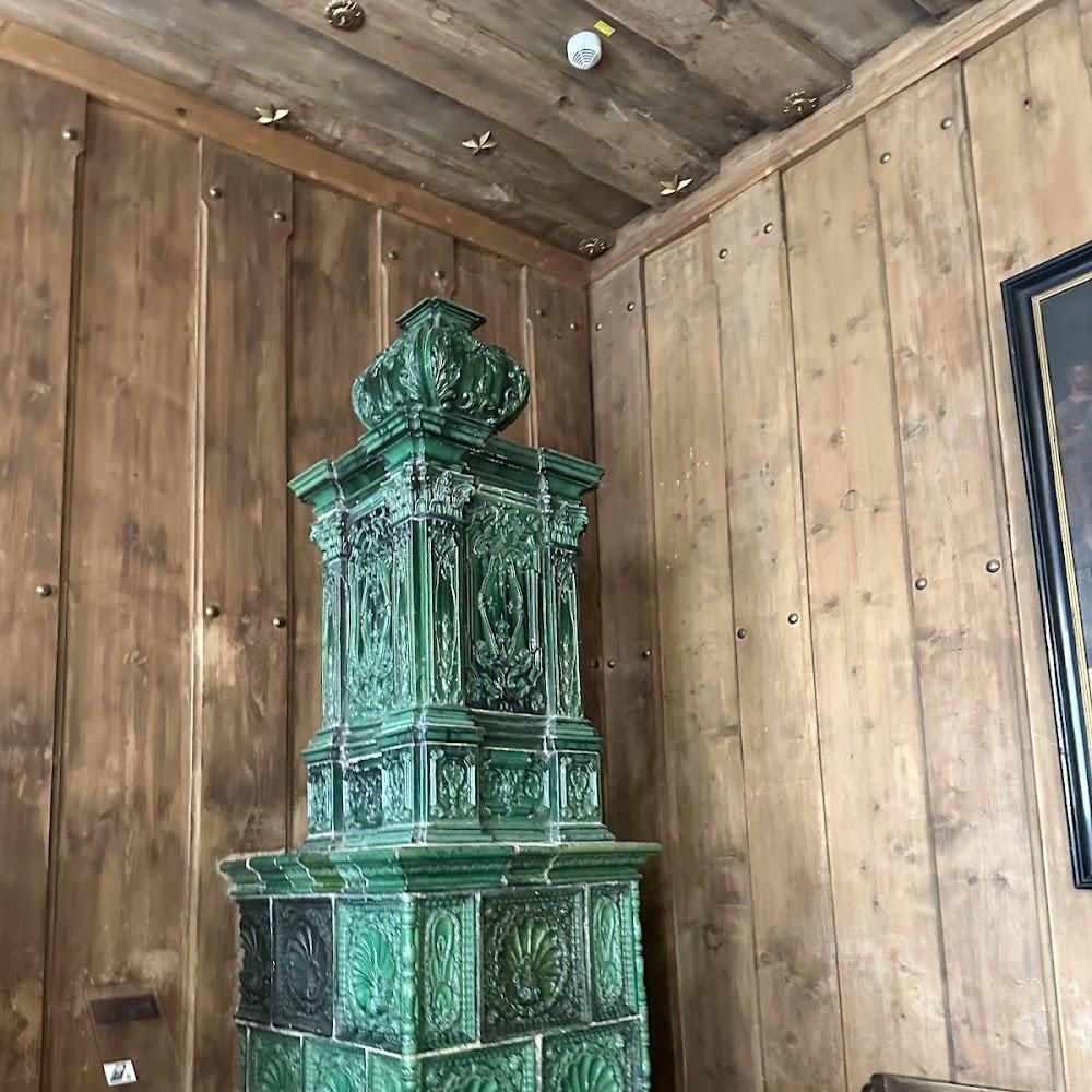 Ornate green tile stove in a wooden room.
